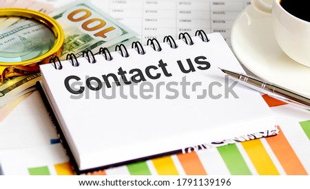 CONTACT US text.Top view office table, Business graph show for marketing plan have book, pen, black coffee, paper clip,magnifier and dollars
