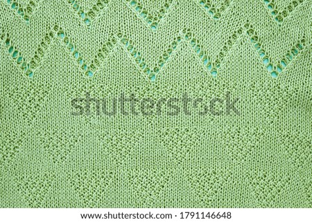 Knitted texture from green yarn. Background for handicraft and hobby goods.