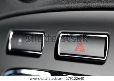 Button of vehicle, car hazard warning flashers button with visible red triangle, visible  fragment of control panel, visible red triangle emergency symbol.