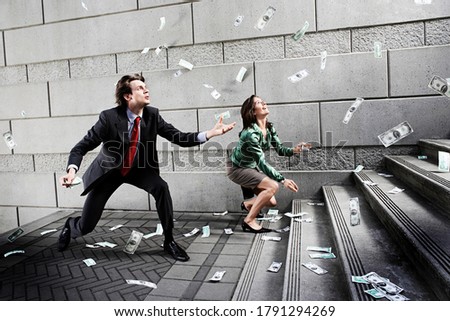 Businessman and woman catching falling money on steps
