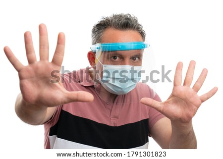 White man wearing protective screen and mask to prevent covid19 contamination making stay away gesture with hands as social distance concept isolated on studio background Royalty-Free Stock Photo #1791301823