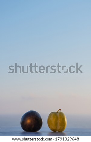 Two fresh black and green peaches on summer sunset sea background. Mediterranean concept. Space for text. Vertical photo