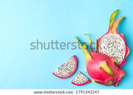 Delicious cut dragon fruit (pitahaya) on light blue background, flat lay. Space for text