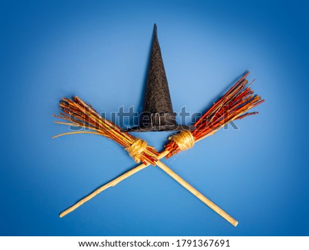 Classic witch black pointed hat and two crossed flying brooms