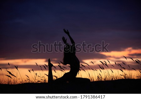 Silhouette of a beautiful young woman practices yoga outdoor at night