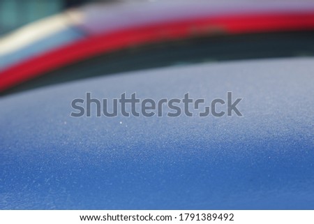 hoar on the blue car's roof and red background. natural texture, creative nature.