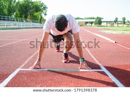 Runner in the starting block on athletic tracks. Horizontal photo