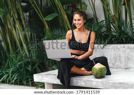 Woman freelance work typing on laptop poolside outdoors with fresh coconut . Traveling with a computer wifi always in toch, dream life concept.