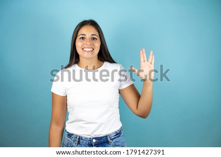 Young beautiful woman over isolated blue background doing hand symbol