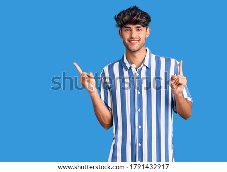 Young hispanic man wearing casual clothes smiling confident pointing with fingers to different directions. copy space for advertisement 