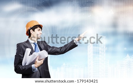 Young man engineer in helmet touching icon of media screen