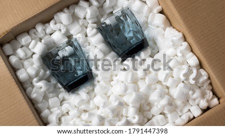 Foam filler for storing and transporting fragile objects.  Glasses in a box. Royalty-Free Stock Photo #1791447398