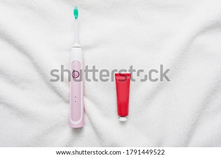 Ultrasonic electric toothbrush and tube of toothpaste, white background. Concept of oral care and healthy teeth by using ultrasonic smart toothbrush