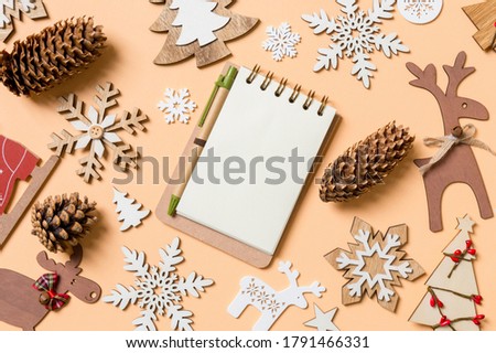 Top view of notebook surrounded with New Year toys and decorations on orange background. Christmas time concept