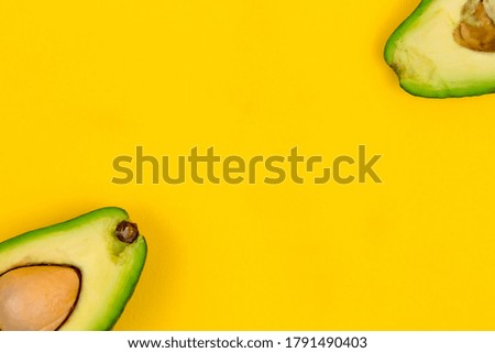 Cut fresh ripe avocado on yellow background.