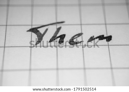 Monochrome macro photo of an inscription them on a squared notebook sheet