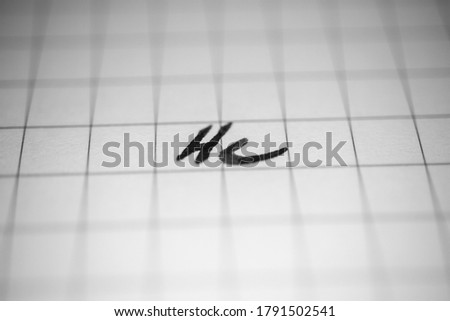 Monochrome macro photo of an inscription he on a squared notebook sheet