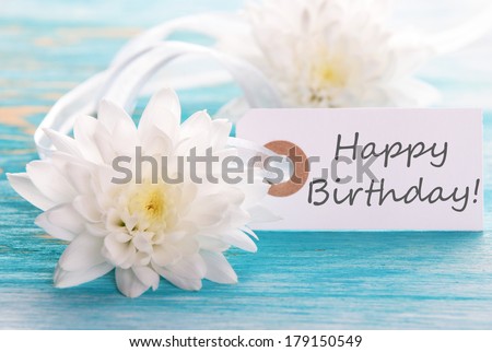 Label with Happy Birthday on wooden turquiose Background with white Flowers