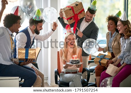 Young woman celebrating birthday in the office with colleagues