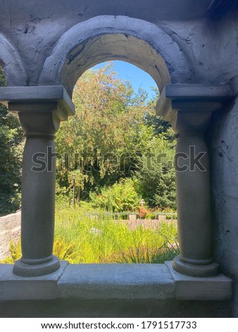 two columns of stone.  arch overlooking a green park with many plants.  beautiful garden in summer on a sunny day.  landscape design. two concrete columns