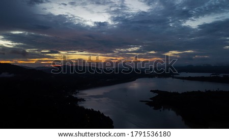 Aerial view of an amazing Colorful and Dramatic sunrise. Majestic Sunlight Cloud fluffy,Idyllic Nature Peaceful Background,Beauty Dark Blue Hour on Dusk,Purple Dawn Silhouette mountain on Kenyir Lake.