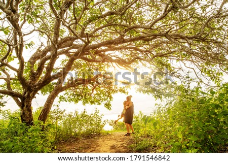 Mom and son on a background of a large tree 