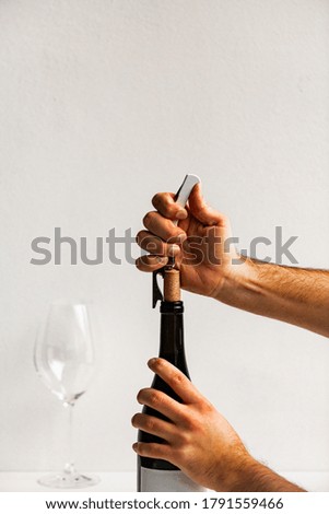A vertical shot of male hands opening a wine bottle with a corkscrew