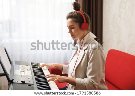 Young and beautiful woman playing synthesizer at home Royalty-Free Stock Photo #1791580586