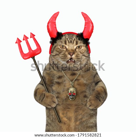 The beige cat in red horns is holding a devil trident for Halloween.  White background. Isolated.