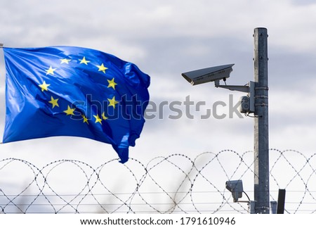European union flag and EU border with surveillance camera and barbed wire, concept picture