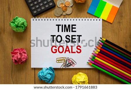 White note with inscription 'time to set goals' on beautiful wooden table, colored paper, colored pencils, paper clips, coins and calculator. Business concept.