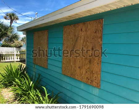 Homemade plywood shutters cover a beach cottage’s windows in preparation for an oncoming hurricane in Florida.￼