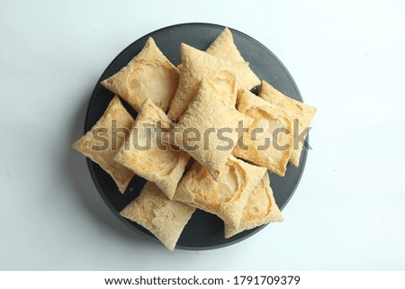A top view of a pile of square puff biscuits on a black pastry stand