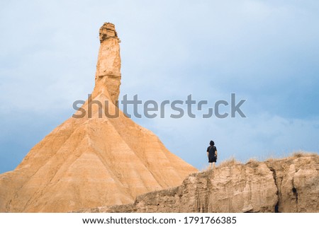 man standing in front of huge orange sandstone in desert with blue sky
