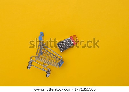 Supermarket trolley with mini grater on yellow background.