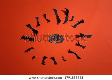 Paper cut Flying bats and halloween pumpkin on orange bright background. Halloween background. Top view. Flat lay
