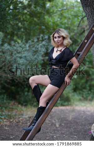 Portrait of blonde woman in black outfit in the park