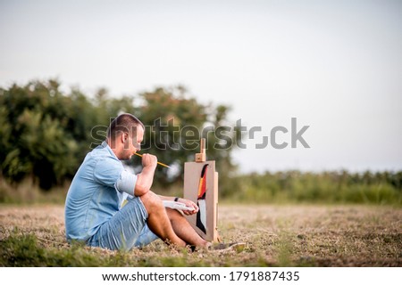 Young Caucasian man painting in nature