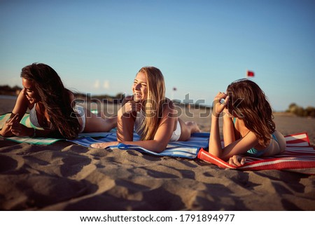 Three girlfriends tanning and relaxing on the beach