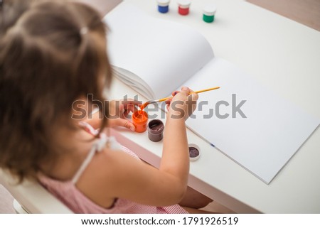 top view a girl paints at a table
