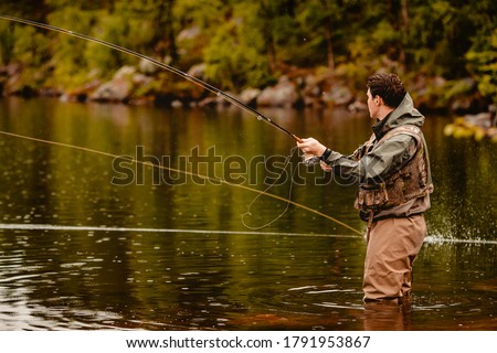 Fisherman using rod fly fishing in mountain river. Royalty-Free Stock Photo #1791953867