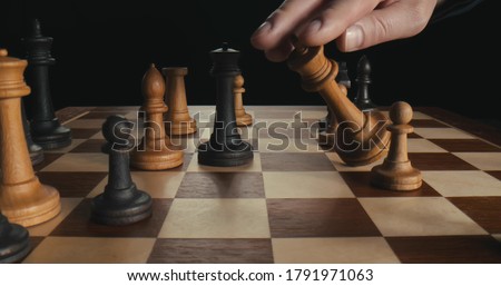 Close up of businessmen playing chess. Black figures win checkmate. Side view of black queen defeating white king during chess game isolated on black background