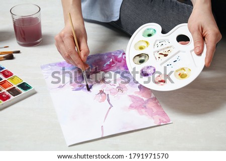 Woman painting flowers with watercolor on floor, closeup