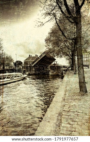 Tourist boat on the canal of Amsterdam in historic city centre. Amsterdam drawbridge in an half-open position while the water-bus is passing by. Vintage style toned picture
