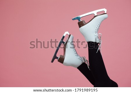 Figure skating is a winter sport and leisure. Women's feet in ice dancing skates. Female figure skater, legs on a pink background.