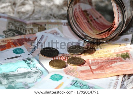 Russian money in banknotes and coins are on the floor, a bundle of money is in a glass jar.
