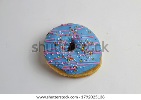 Selective focus of a Donut topped with blue glaze and sprinkler on a white background.