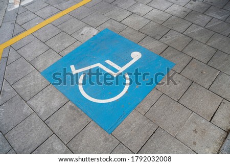 Parking spot for disabled persons marked on a tiled pavement