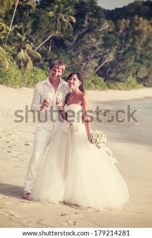 newlyweds with wedding bouquet of jasmine on the beach in the Seychelles