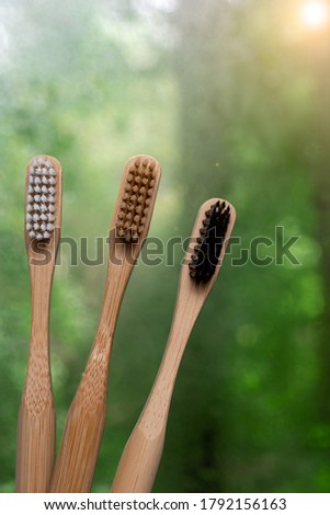 three bamboo toothbrushes close-up on a green background. environmentally friendly hygiene items. vertical photography.